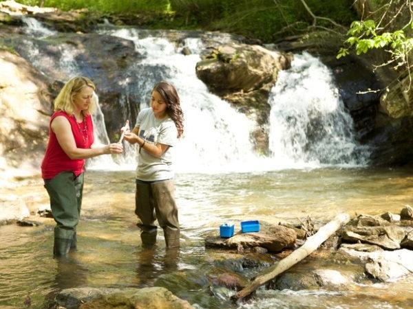 a couple of women standing next to a waterfall